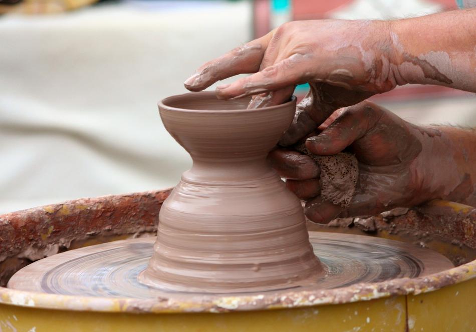 hands on pottery wheel close up on blurred background