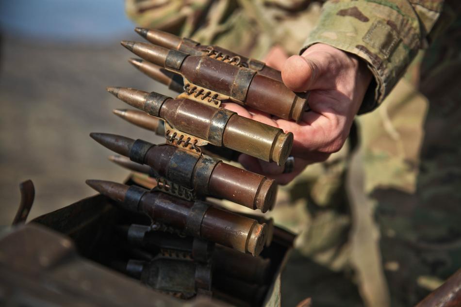 Close-up of the cartridge, with the bullets, in the hand of a soldier, in light