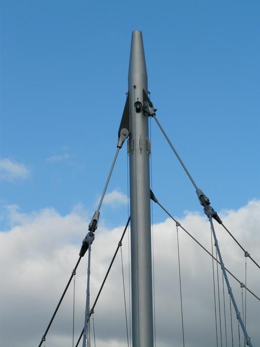 Steel bridge, with the masts, at blue sky with clouds on background