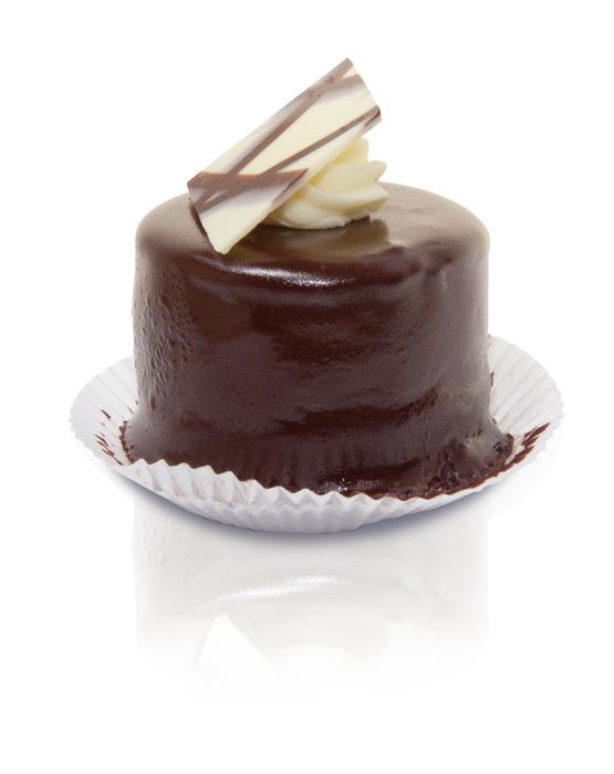 Beautiful, chocolate tart cake with the white chocolate decorations, on the white paper, at white background