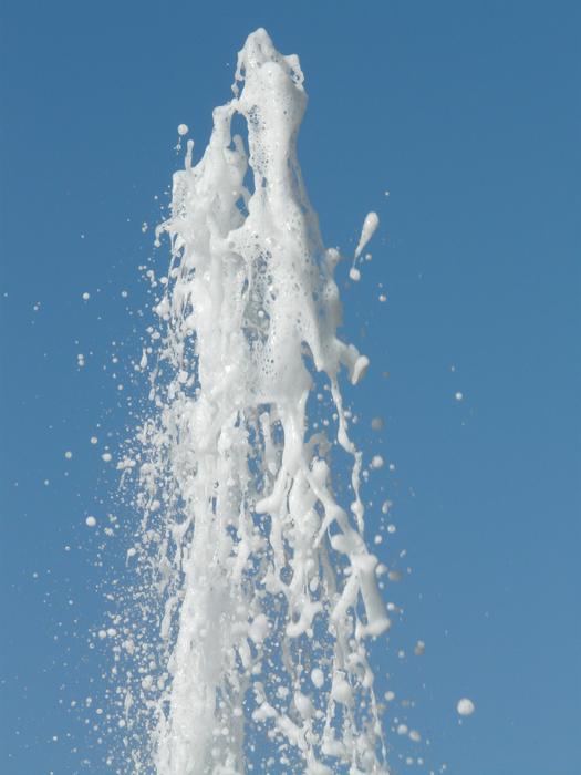 Beautiful, white jet of the foam, at blue sky on background