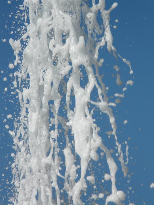 White, pouring foam, at background of the blue sky