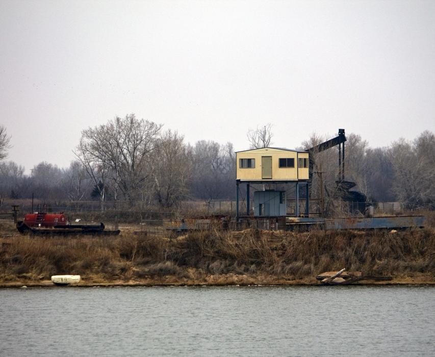 Landscape with the oil rig on the water shore, among the colorful plants