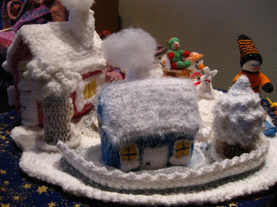 knitted houses with snow next to figures of people