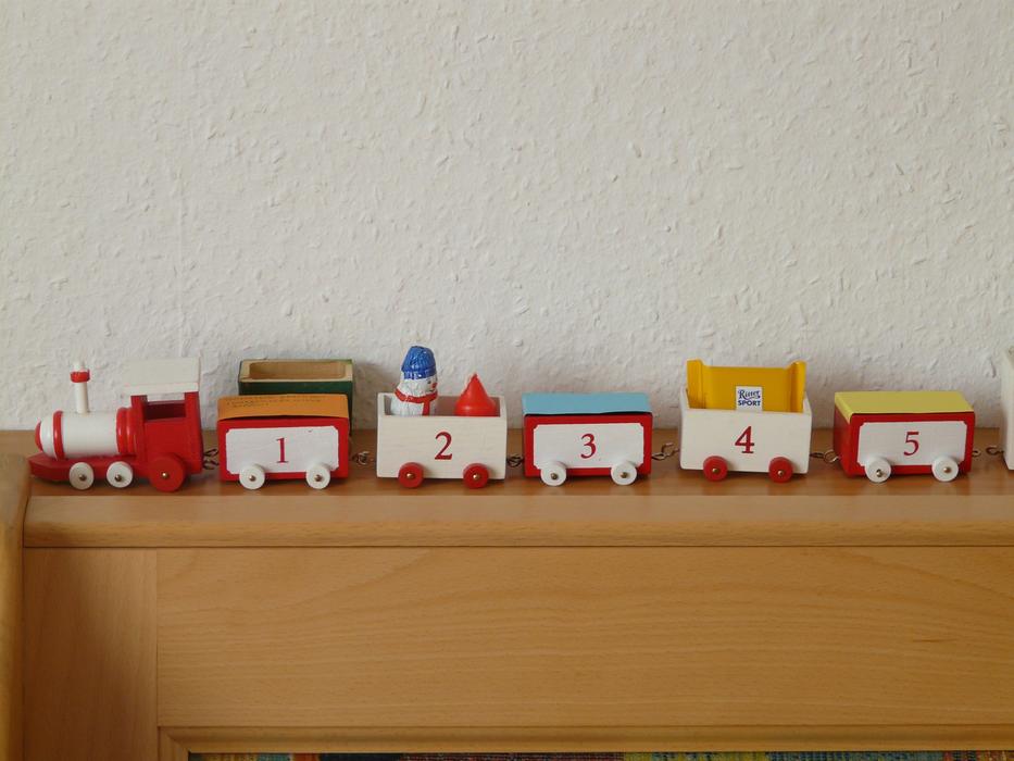 Colorful train with numbers, on the wooden furniture, near the white wall