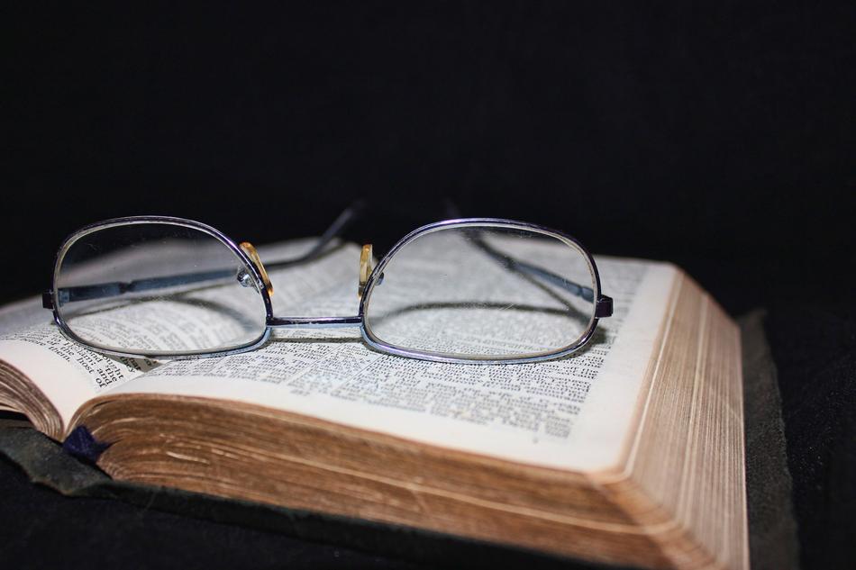 vintage Glasses on open bible at darkness