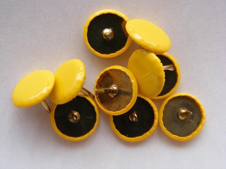 Pile of the yellow drawing pins, on the white surface