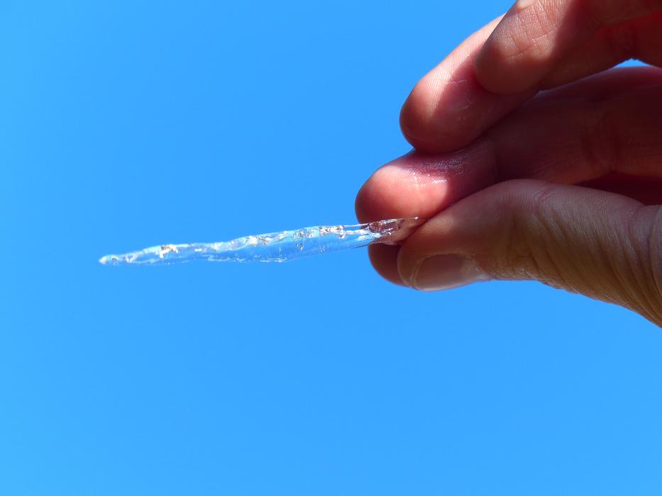 icicle in hand against blue sky