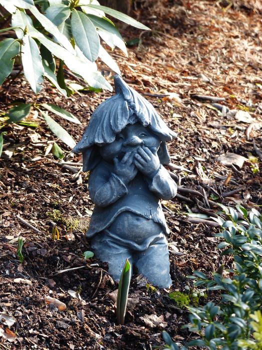 grimace of a stone gnome in the autumn garden