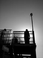 silhouette of a man standing near a metal fence in the evening