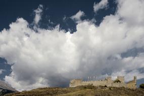 castle on a hill under big white clouds