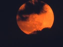 orange full moon in black clouds