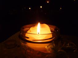 Close-up of the beautiful, burning candle in the glass, at dark background with colorful lights