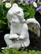 statue of a sad angel among flowers at the grave