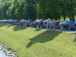 People near the colorful sales booths, near the beautiful, green trees in Salzburg, Austria