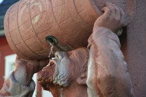 Statue of the man, holding wine barrel and drinking
