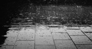 Black and white photo of the pavement in rain water drops