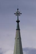 spire with a cross on the background of a cloudy sky