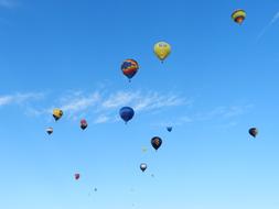 Colorful, patterned, flying hot air balloons under the blue sky with clouds