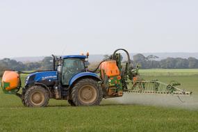 blue tractor with sprayers on green field