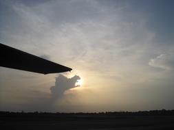 Aircraft with the wing, on the landscape in Burundi, Africa, at colorful sunset with clouds