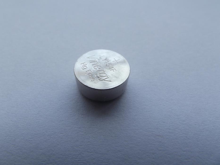 wristwatch battery on gray table