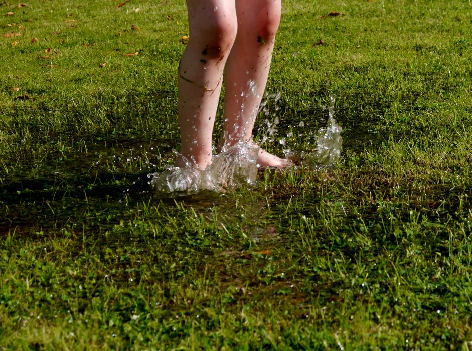 baby feet in a puddle in the meadow