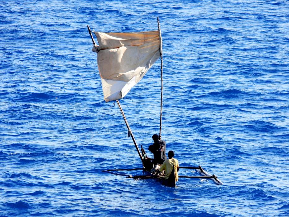 Fishermen on the dugout with sale, on the blue water with ripple