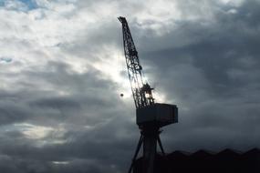 Crane Lifting Construction at storm clouds