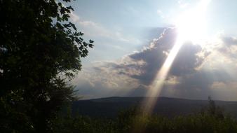 sunbeam through gray cloud over scenic landscape