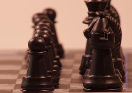 black chess pieces close up in blurred background