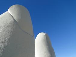 White fingers of the sculpture in Punta Del Este, Uruguay, in sunlight, under the blue sky