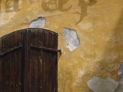 Wooden door in the old, yellow wall in light and shadow, in Prague, Czech Republic