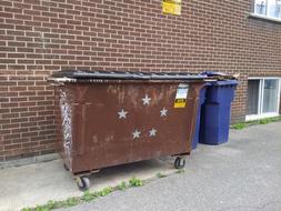 Trash containers near the building with windows