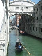 Gondolier on the beautiful canal, near the Bridge of Sighs among the buildings, in sunlight