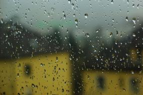 View with buildings, in rain, behind the window with water droplets