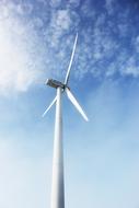 White windmill in sunlight and shadow, under the blue sky with white clouds