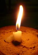 Close-up of the colorful, burning candle, among the darkness