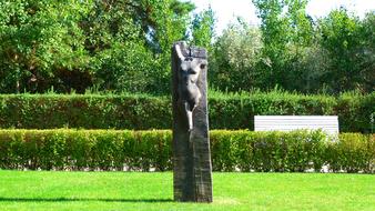 Statue with body, among the colorful and beautiful plants, in sunlight