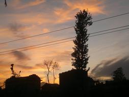 Silhouettes of the houses and plants on landscape in Nepal, at colorful and beautiful sunset with clouds