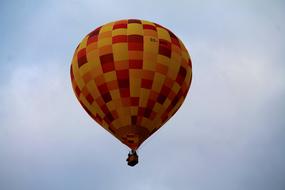 orange yellow hot air balloon high in the sky