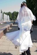 the groom holds the bride in his arms near the fountain