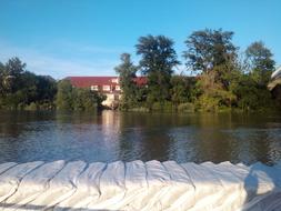 Sand bags near the Danube River, colorful plants and buildings in Budapest, Hungary, under the blue sky