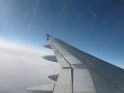 airplane wing on a sunny day in the clouds