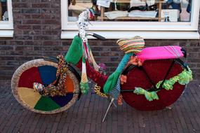 bicycle in colored fabric on the street near the house