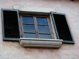 Close-up of the old window with dark shutters, in the building