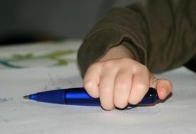 blue pen in child's hand in blurred background