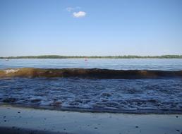 Beautiful landscape of the beach of the river, with ripple, under the blue sky with clouds
