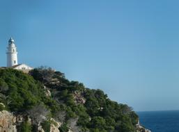 Beautiful landscape of the coast cliff with lighthouse and green plants, under the blue sky