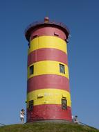 yellow-red lighthouse on a hill on a sunny day